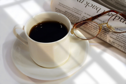Table with morning newspaper, coffee, and reading glasses